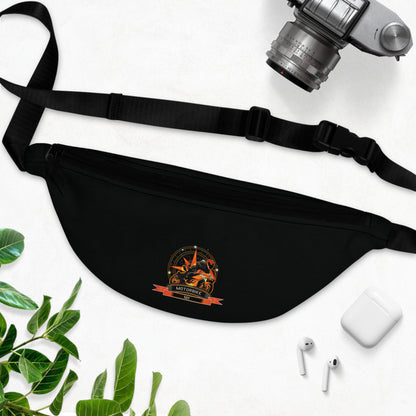 Black fanny pack with a logo on a white surface with a camera, phone, and leaves.